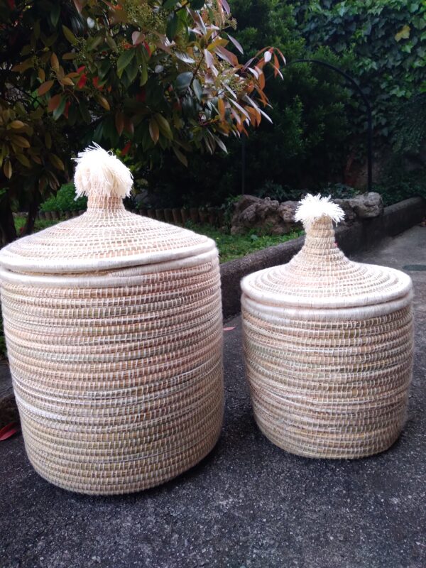 Photo d'une corbeille en doum(palmier nain) en fibres végétales et brodées d'un fil de laine écru. Idéale pour le linge de la maison, ou bien dans une chambre d'enfant. Cette corbeille possède un couvercle.