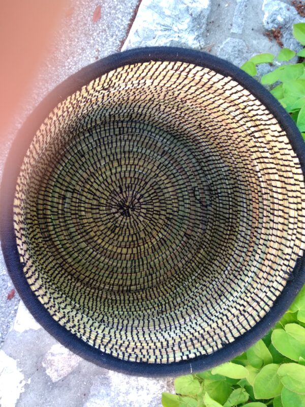 Photo d'une corbeille en doum(palmier nain) en fibres végétales et brodées d'un fil de laine noire. Idéale pour le linge de la maison, ou bien dans une chambre d'enfant. Cette corbeille possède un couvercle.