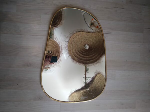 Photographie d'un miroir ovale destructuré avec un contour cuivre. Réalisé entièrement à la main par les artisans de Marrakech. Le miroir est un incontournable de la décoration d'intérieur.