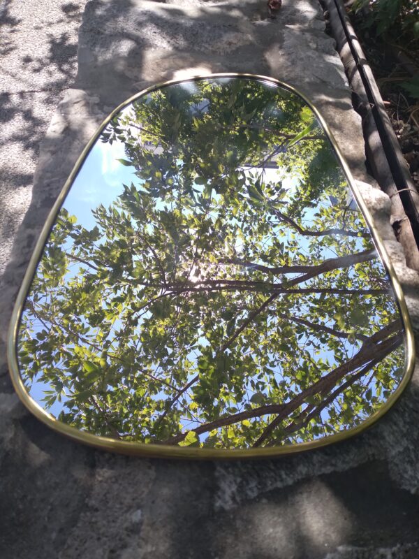 Photographie d'un miroir ovale destructuré avec un contour cuivre. Réalisé entièrement à la main par les artisans de Marrakech. Le miroir est un incontournable de la décoration d'intérieur.