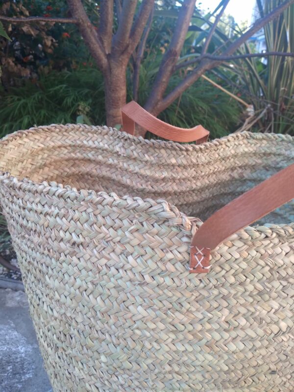 Photo d'un panier à linge en fibre végétale de palmier avec anses en cuir. Très utilisé au Maroc pour la vannerie. Il est résistant, ne craint pas l'eau, il devient un vrai allié pour tout ranger dans la maison.