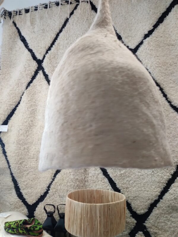 Photographie d'une suspension en feutre de laine en forme de cloche taupe. La laine est modelée à la main jusqu'à ce qu'elle devienne ce qu'on appelle de la laine feutrée. Avec ce luminaire, vous pouvez créer une ambiance naturelle et chaleureuse dans votre intérieur.
