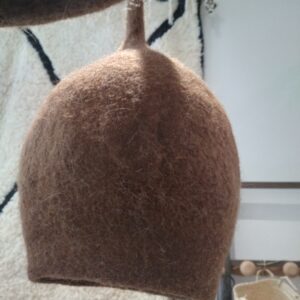 Photographie d'une suspension en feutre de laine en forme de boule taupe. La laine est modelée à la main jusqu'à ce qu'elle devienne ce qu'on appelle de la laine feutrée. Avec ce luminaire, vous pouvez créer une ambiance naturelle et chaleureuse dans votre intérieur.