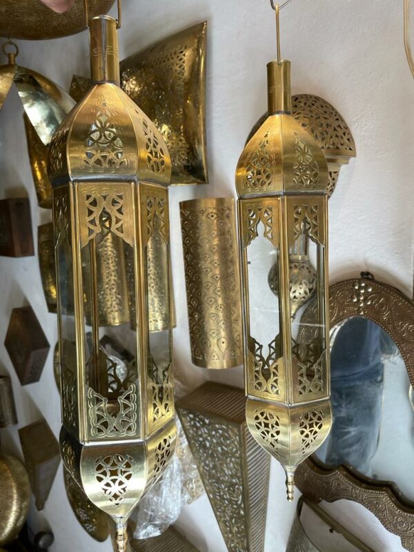 Photo d'une lanterne en cuivre jaune, elle est toute en longueur, finement ciselé par un artisan de Marrakech au Maroc
