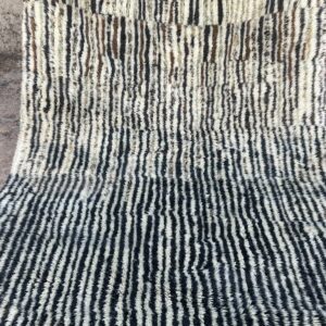 Photo d'un tapis Mrirt rayé camaïeu de bleu et gris, ligne géométrique, sur fond écru. Les tapis Mrirt sont tissé avec des nœuds doubles ce qui en fait des tapis particulièrement dense. 200 x 150. 650€