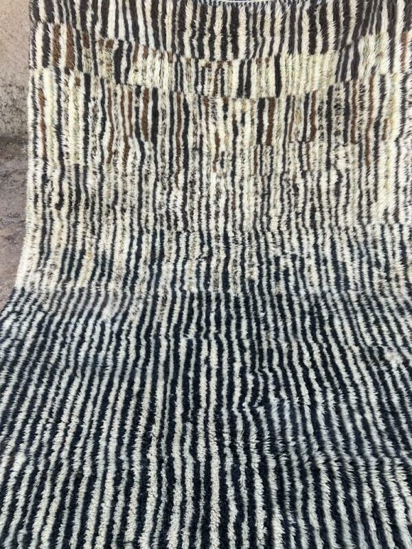 Photo d'un tapis Mrirt rayé camaïeu de bleu et gris, ligne géométrique, sur fond écru. Les tapis Mrirt sont tissé avec des nœuds doubles ce qui en fait des tapis particulièrement dense. 200 x 150. 650€