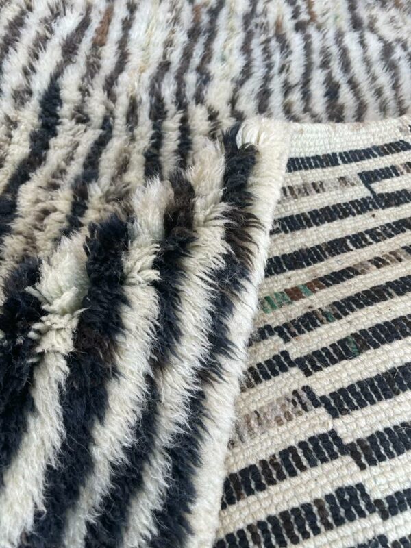 Photo d'un tapis Mrirt rayé camaïeu de bleu et gris, ligne géométrique, sur fond écru. Les tapis Mrirt sont tissé avec des nœuds doubles ce qui en fait des tapis particulièrement dense. 200 x 150. 650€