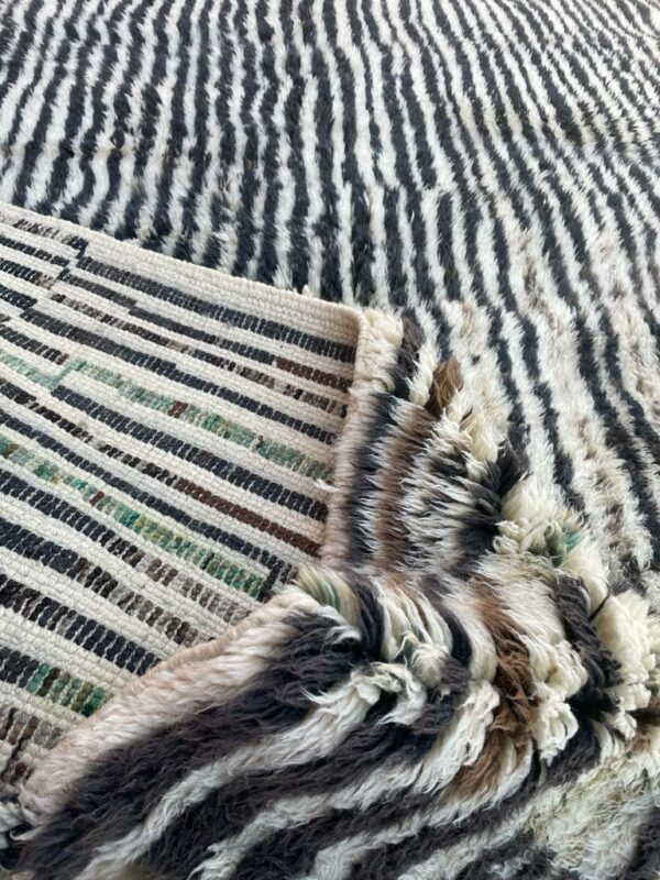 Photo d'un tapis Mrirt rayé camaïeu de bleu et gris, ligne géométrique, sur fond écru. Les tapis Mrirt sont tissé avec des nœuds doubles ce qui en fait des tapis particulièrement dense. 200 x 150. 650€