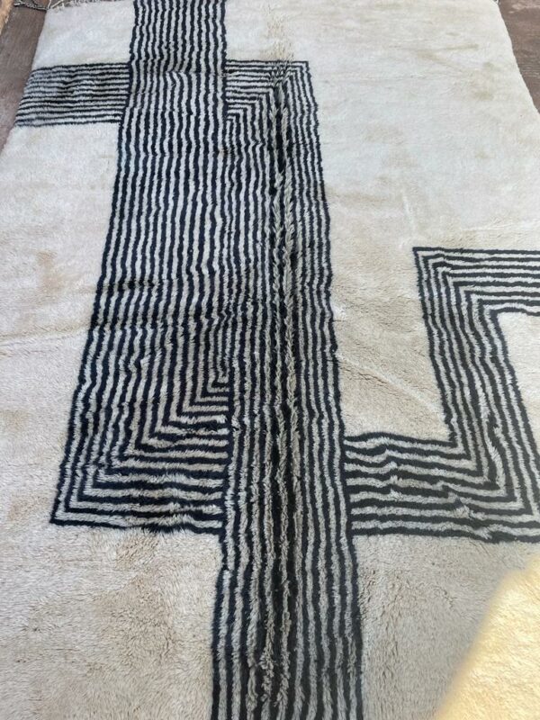 Photo d'un tapis Mrirt rayé camaïeu de bleu et gris, ligne géométrique, sur fond écru. Les tapis Mrirt sont tissé avec des nœuds doubles ce qui en fait des tapis particulièrement dense.