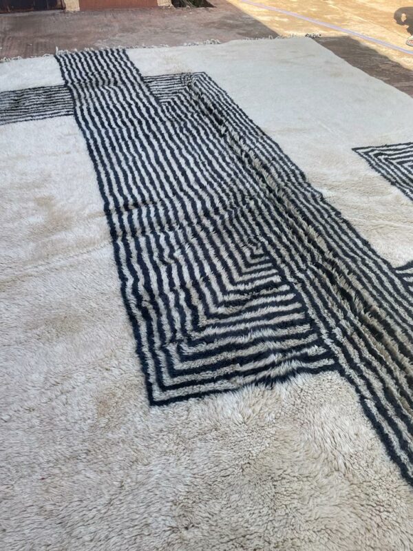 Photo d'un tapis Mrirt rayé camaïeu de bleu et gris, ligne géométrique, sur fond écru. Les tapis Mrirt sont tissé avec des nœuds doubles ce qui en fait des tapis particulièrement dense.