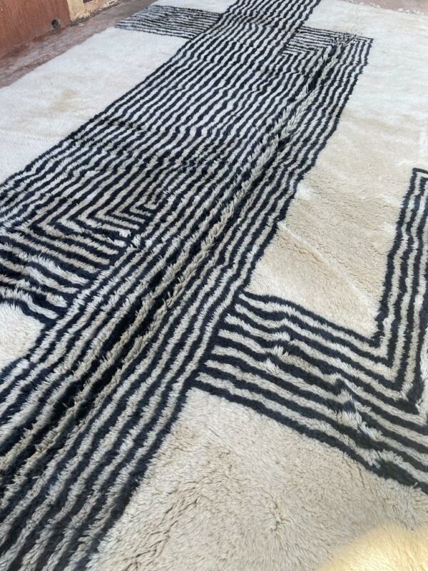 Photo d'un tapis Mrirt rayé camaïeu de bleu et gris, ligne géométrique, sur fond écru. Les tapis Mrirt sont tissé avec des nœuds doubles ce qui en fait des tapis particulièrement dense.