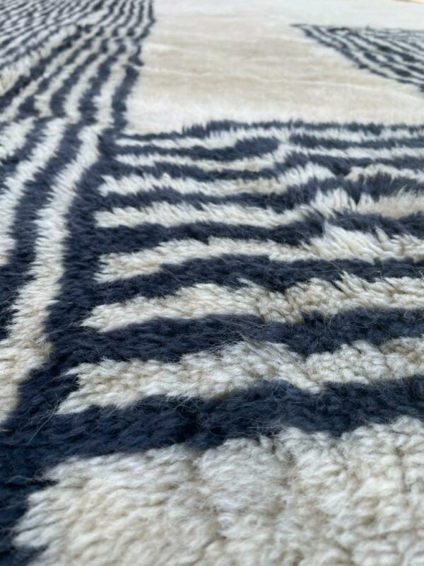 Photo d'un tapis Mrirt blanc avec des lignes géométriques noirs. Les tapis Mrirt sont tissé avec des nœuds doubles ce qui en fait un tapis particulièrement dense. 380 x 270 2190€