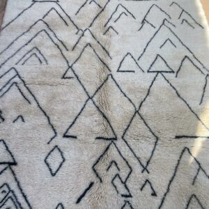 Photo d'un Tapis Mrirt à poil long ( Shaggy ) motif en forme de montagne. Tapis couleur écru et motifs noirs. 300x250.