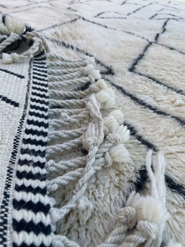 Photo d'un Tapis Mrirt à poil long ( Shaggy ) motif en forme de montagne. Tapis couleur écru et motifs noirs. 300x250.