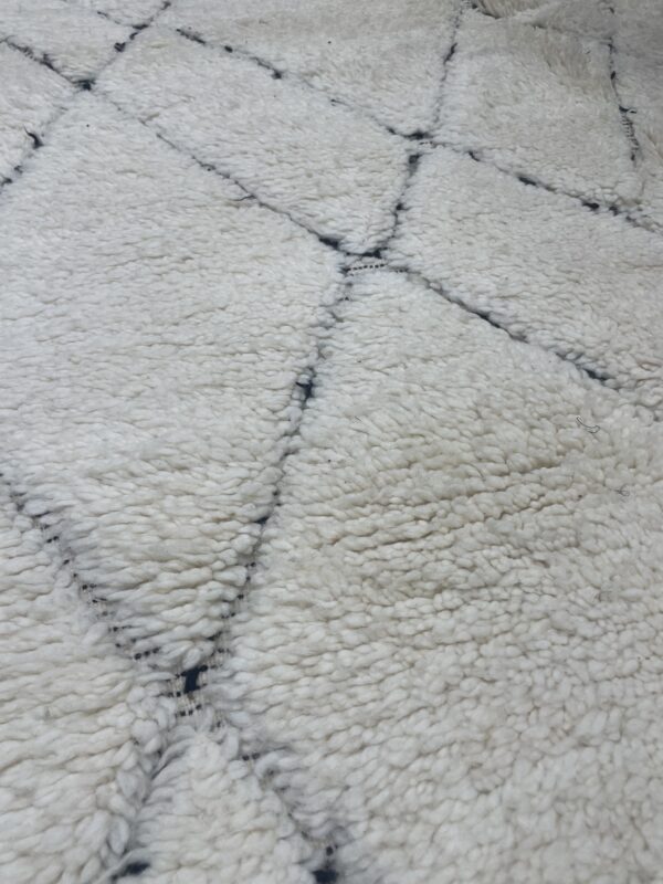 Photo d'un tapis Beniouarain blanc motifs géométrique dans la trame.