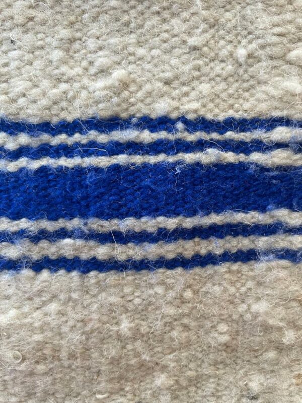 Photographie d'une housse carrée en laine rayer bleu.
