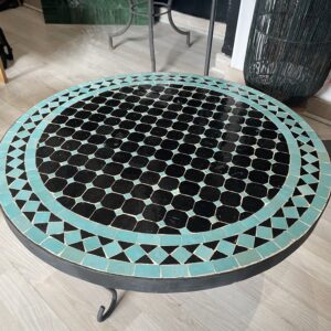 Photo d'une table ronde en zellige turquoise et noir.