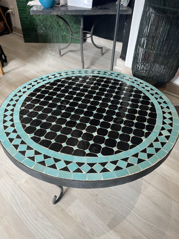 Photo d'une table ronde en zellige turquoise et noir.