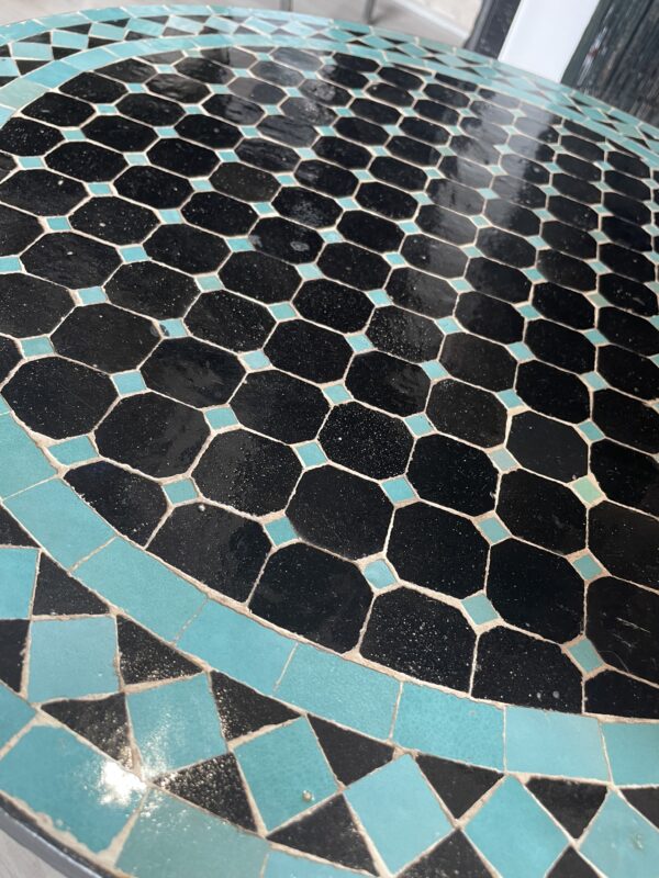 Photo d'une table ronde en zellige turquoise et noir.