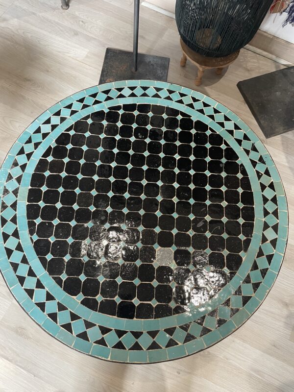 Photo d'une table ronde en zellige turquoise et noir.