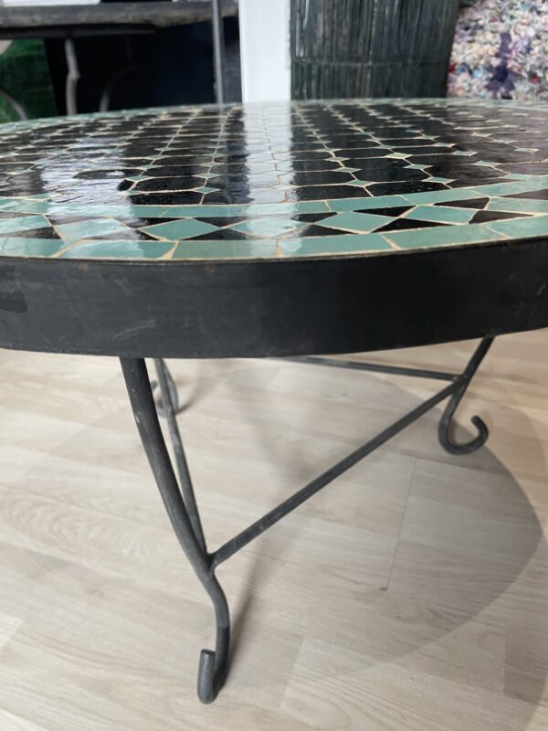 Photo d'une table ronde en zellige turquoise et noir.