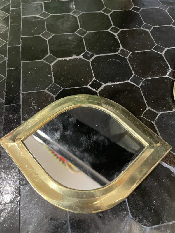 Photographie d'un miroir à sac avec un contour cuivre, en forme de bouche.
