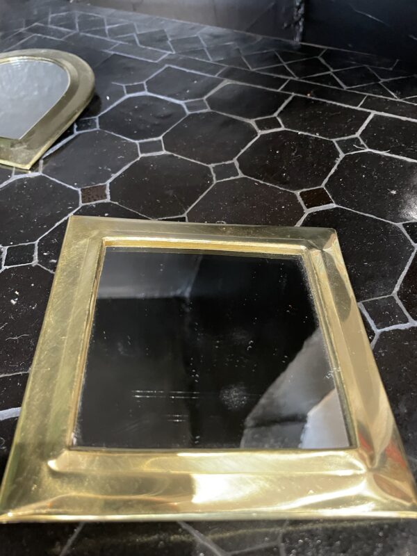 Photographie d'un miroir à sac avec un contour cuivre, en forme carré.