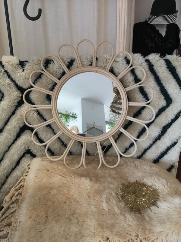Photographie d'un miroir rond en osier en forme de fleur les pétales.