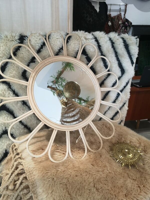 Photographie d'un miroir rond en osier en forme de fleur. les pétales. sont arrondies.