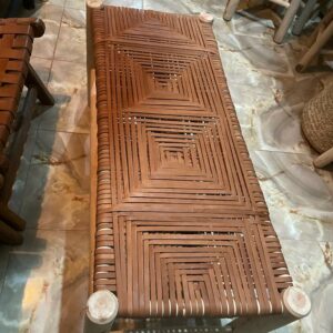 Photographie d'un banc en cuir tressé avec de fine lamelle de peau, couleur Kamel, tres jolie réalisation. les lamelle forme des motifs graphique.