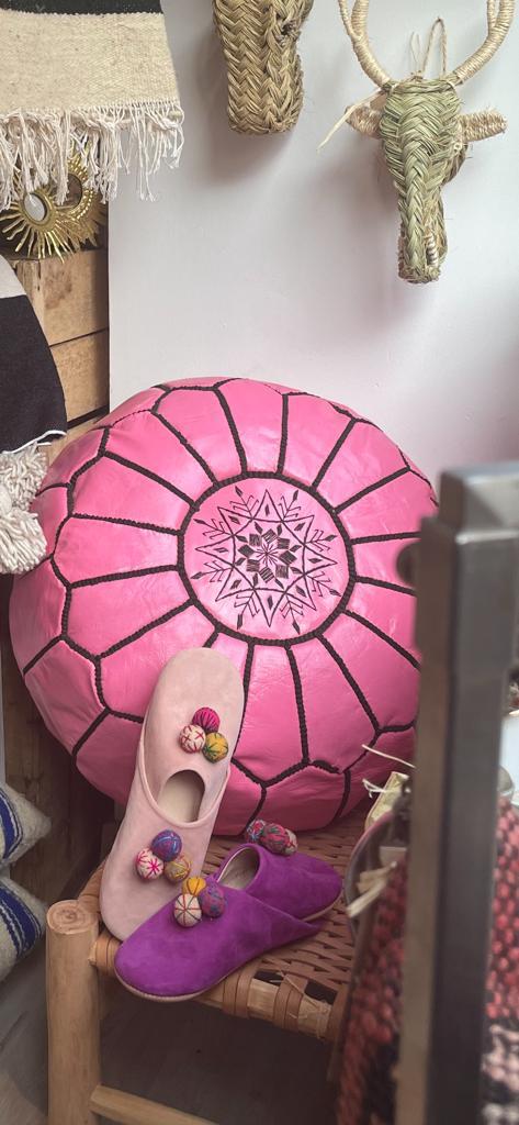 Photo d'un pouf en cuir rose marocain, il est brodé de large bande noir, au centre un rond brodé entoure une rosasse brodé. Sa couleur lui donne plus de modernité, et du pep's dans un intérieur.