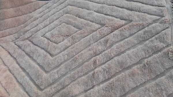 Photo d'un tapis Mrirt beige rosé. 310x215. Tapis entièrement réalisé en laine, avec des doubles nœuds, il est dense, épais, sa texture est douce et soyeuse. Le tapis Mrirt est le tapis contemporain le plus luxueux est un des plus beau du Maroc. confectionné dans les montagnes du moyen Atlas.