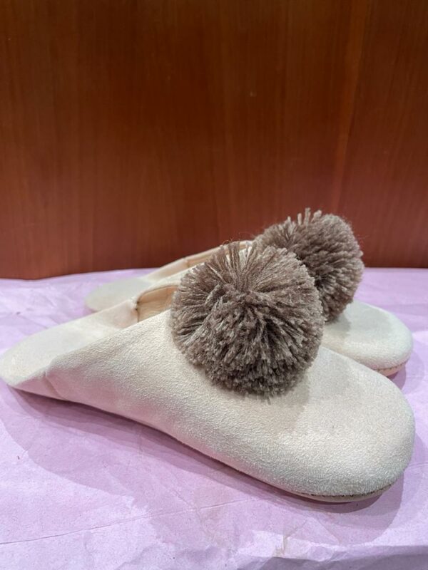 Photo d'une paire de babouche rose pale avec pompons.