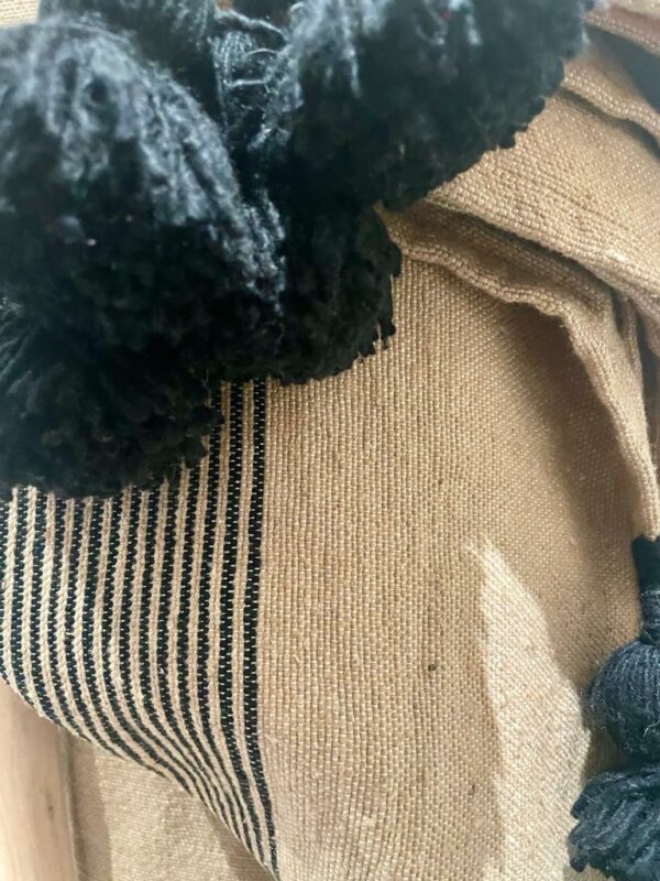 Photo d'un plaid en coton beige avec rayure noire.