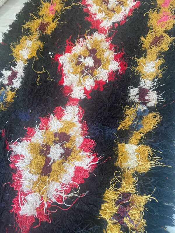Photo d'un tapis boucherouite fond noir motifs berbère.